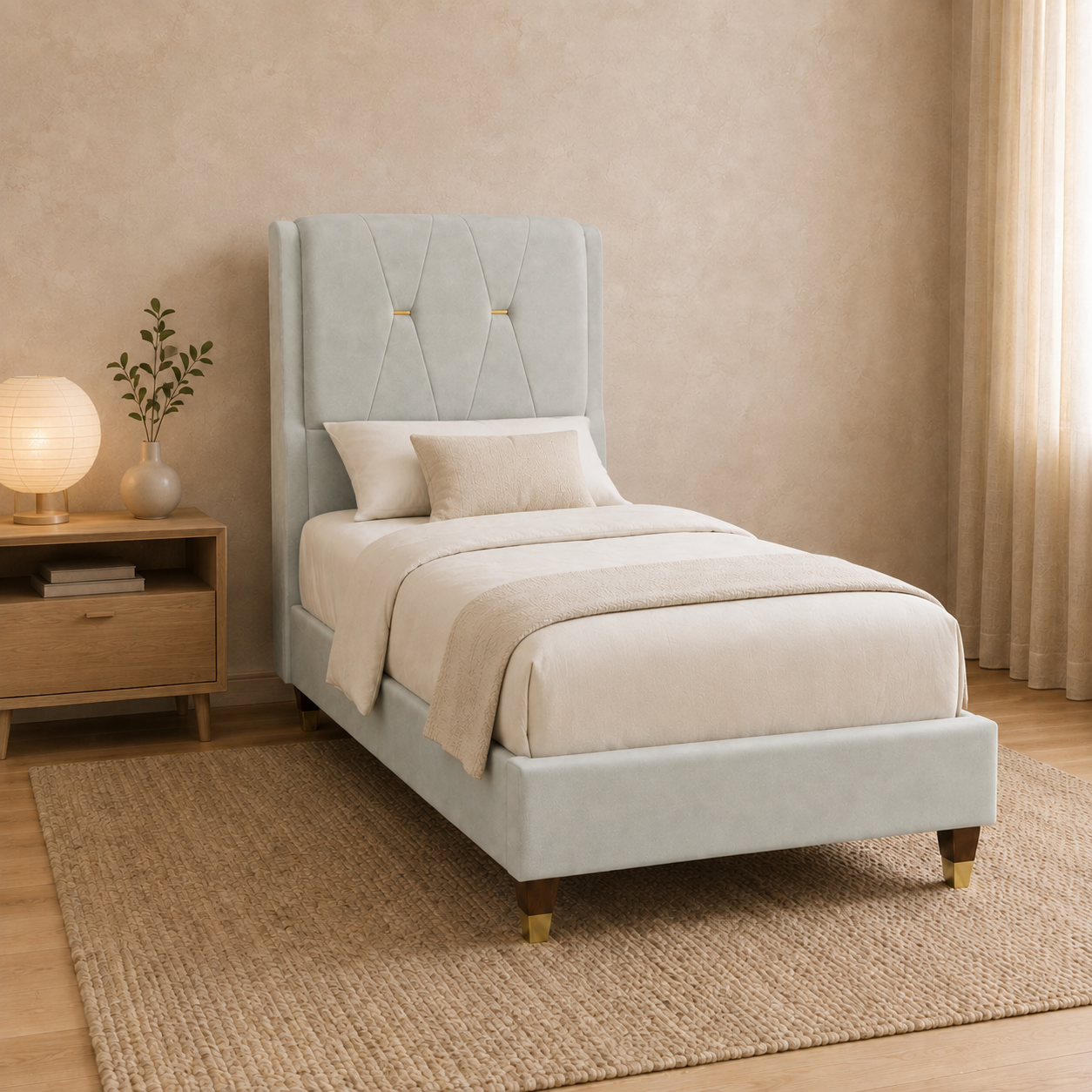 A light blue upholstered single bed with a tall tufted headboard and wooden legs, styled in a warm beige bedroom with a wooden nightstand, lamp, and woven rug.