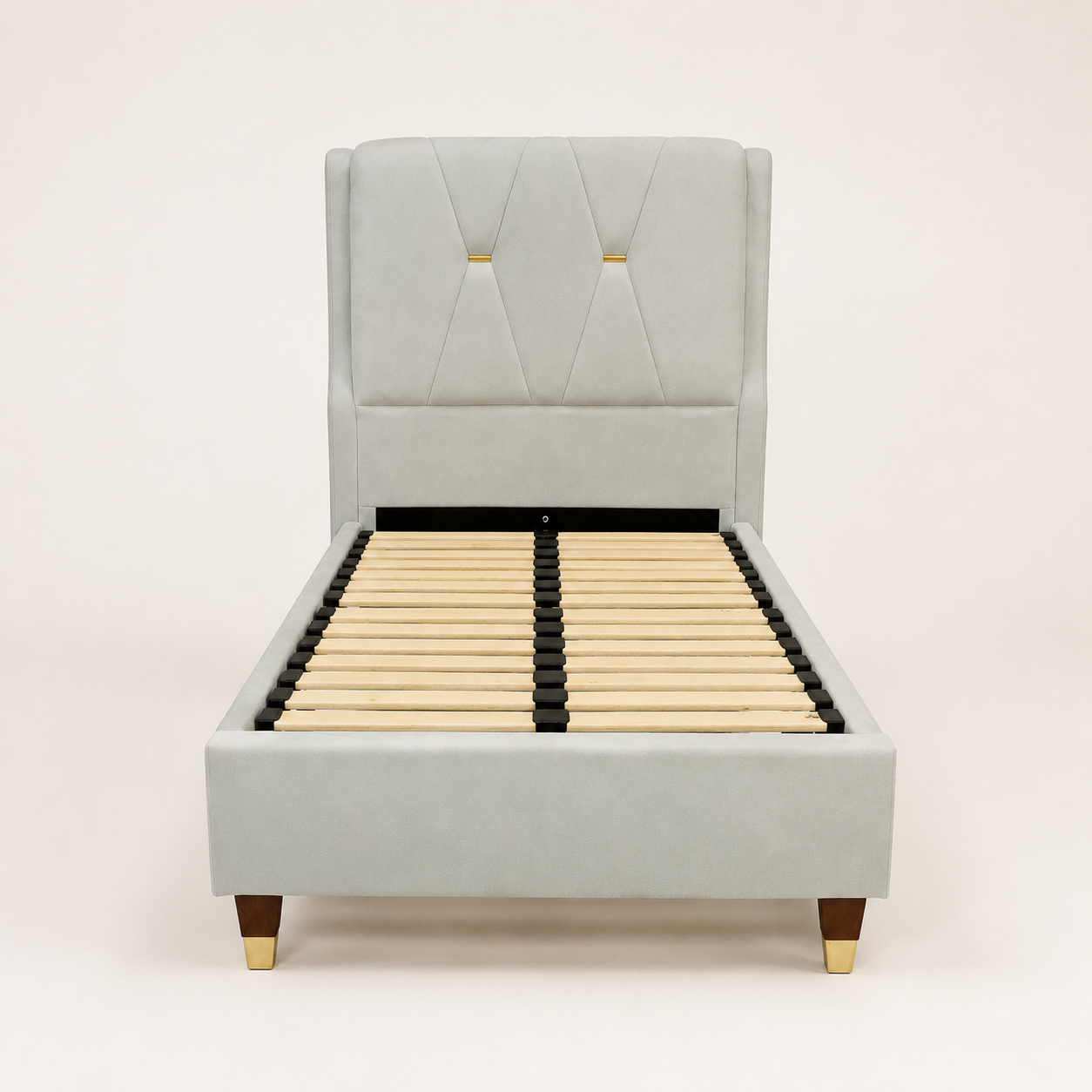 A light gray upholstered bed frame with a tall tufted headboard, wooden slats, and dark legs with gold-toned caps, shown against a plain light background.