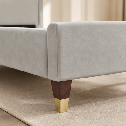 Close view of RANIYA's light grey suede footboard and gold-capped dark wooden leg
