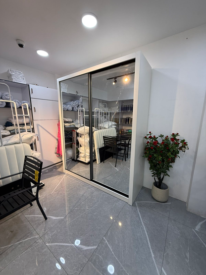 Actual AIDA 1.8 m wardrobe in the showroom, showing its white side panel and two full-length mirrored sliding doors