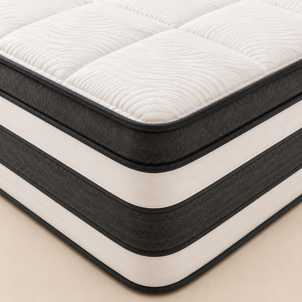 A close-up of a mattress corner showing a quilted white top surface, dark charcoal side panels, and cream-colored horizontal stripes, set against a light beige background.